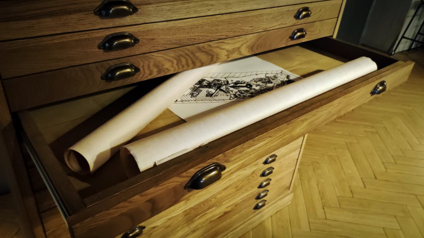 Открытый ящик чертёжного шкафа с рулонами бумаги и графическими листами