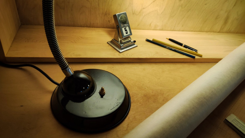 Настольная лампа, календарь и чертёжные принадлежности на рабочем месте инженера