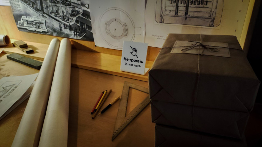 Рабочий стол инженера с рулонами бумаги и табличкой «Не трогать» в павильоне «АТОМ»