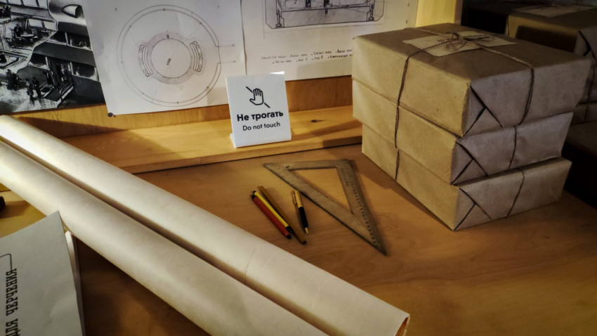 Чертёжные материалы и технические схемы рядом с табличкой «Не трогать»