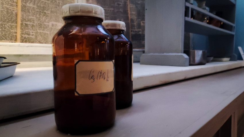 Коричневые лабораторные бутылки с маркировкой на фоне стен исторической экспозиции