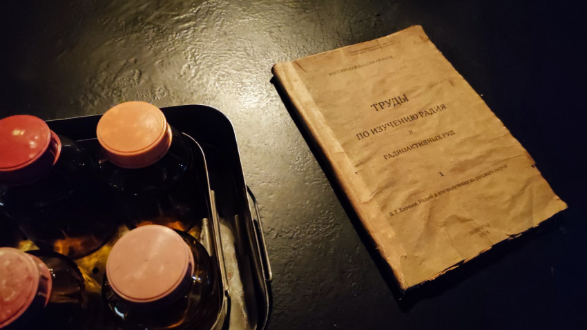 Книга о радиt и радиоактивных рудах рядом с лабораторными флаконами