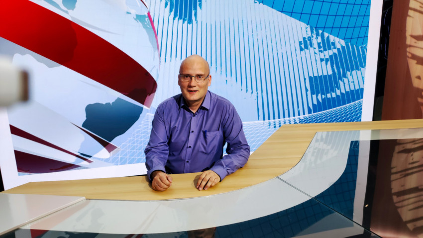 Посетитель за новостным столом в стилизованной студии экспозиции