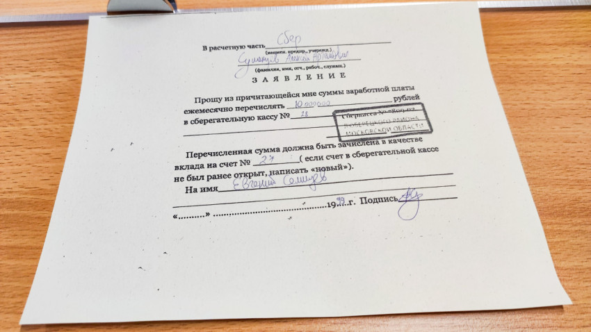 Рукописное заявление на банковский вклад на деревянном столе