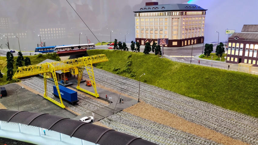 Грузовой терминал с жёлтым краном и железнодорожными путями на масштабном макете