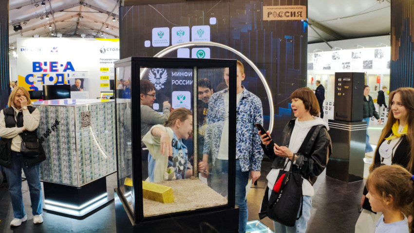 Группа посетителей у интерактивного стенда Минфина России с макетом золотого слитка