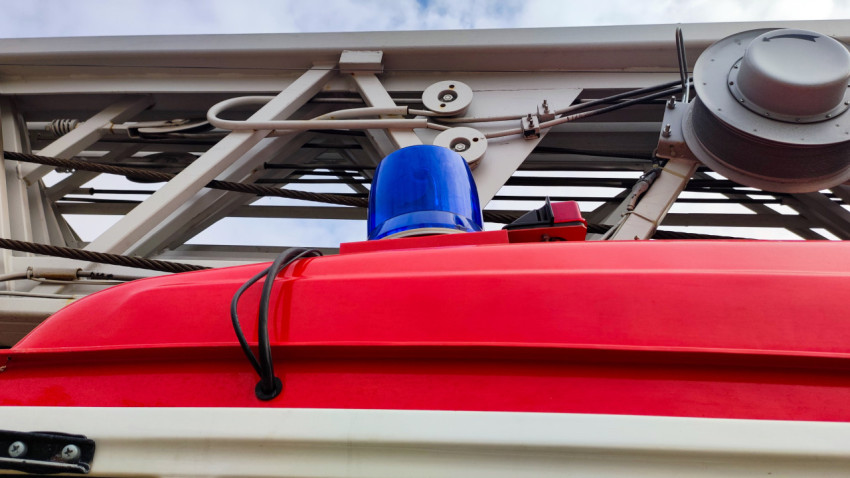 Синий маяк пожарной авто­лестницы под металлической конструкцией