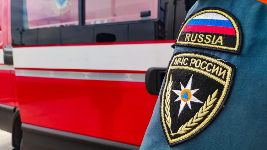 Плечевой шеврон сотрудника МЧС России на фоне пожарного автомобиля