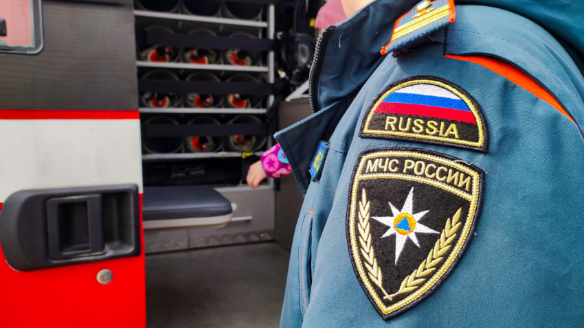 Наплечный шеврон сотрудника МЧС России рядом с оборудованием пожарного автомобиля