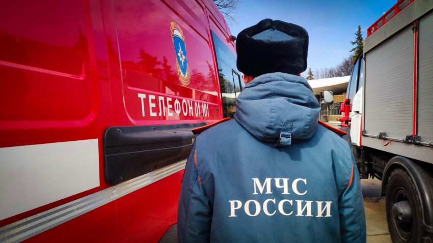 Спасатель МЧС России у борта пожарного автомобиля с номером экстренной службы