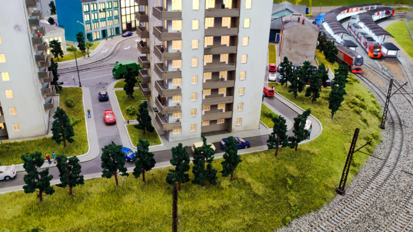 Макет жилого дома рядом с железнодорожной линией и городскими улицами