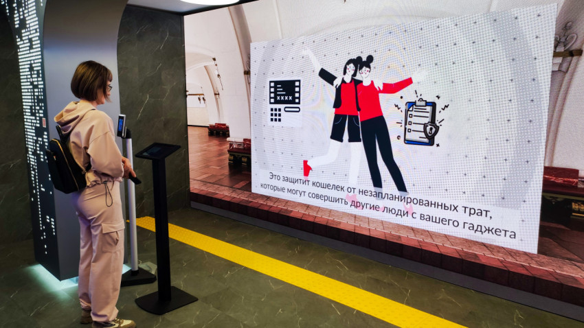 Посетитель у стенда с экраном о защите расходов с помощью биометрии