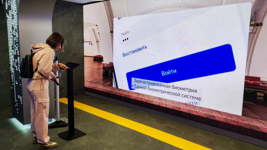 Посетитель взаимодействует с терминалом перед экраном о биометрической авторизации