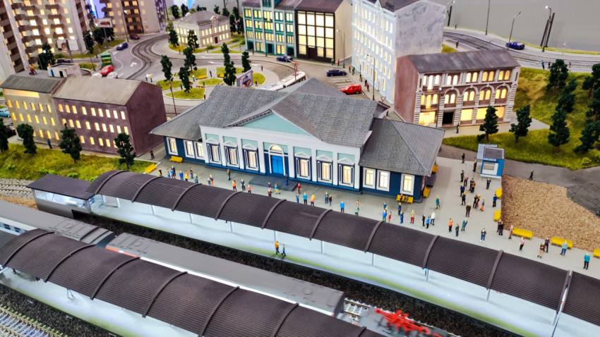 Макет городской станции с модельными зданиями и движущимися поездами