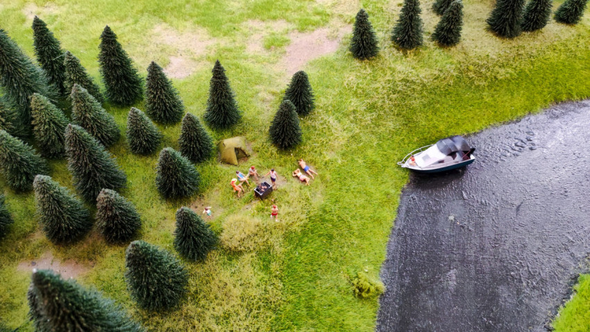 Макет лесной стоянки у воды с лодкой и группой отдыхающих