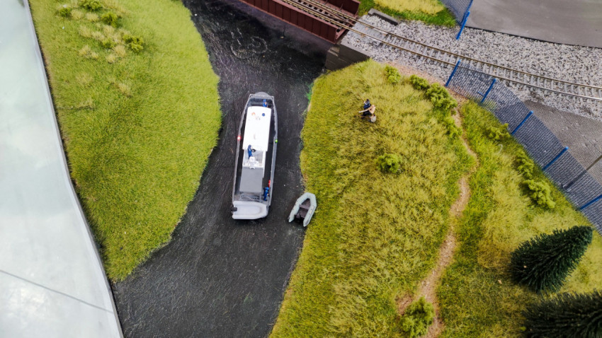 Макет реки с моторной лодкой и береговой тропой