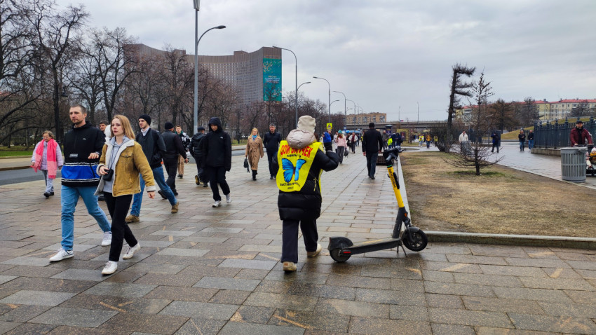 Поток людей на аллеях ВДНХ и сотрудник сервиса самокатов
