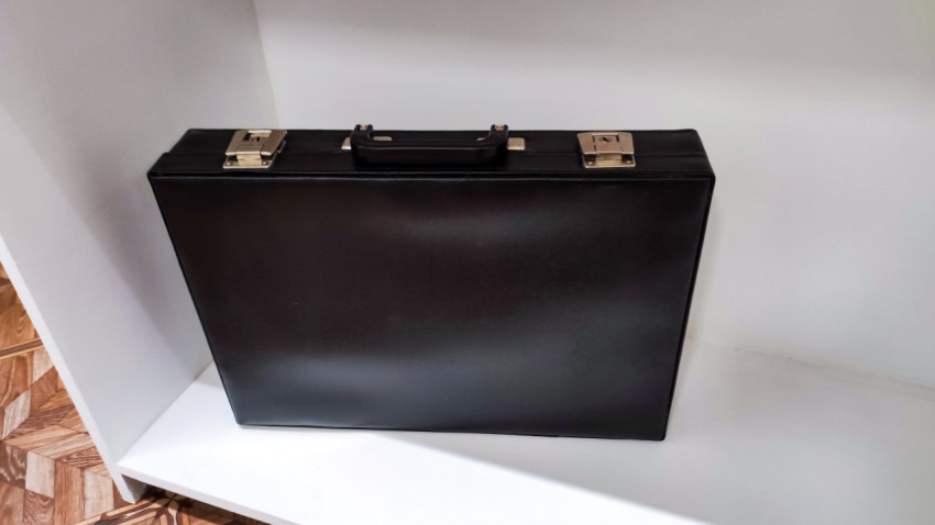 Чёрный портфель на белой полке экспозиции