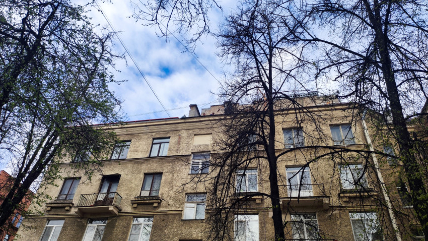 Фасад жилого дома с балконами и деревьями на переднем плане