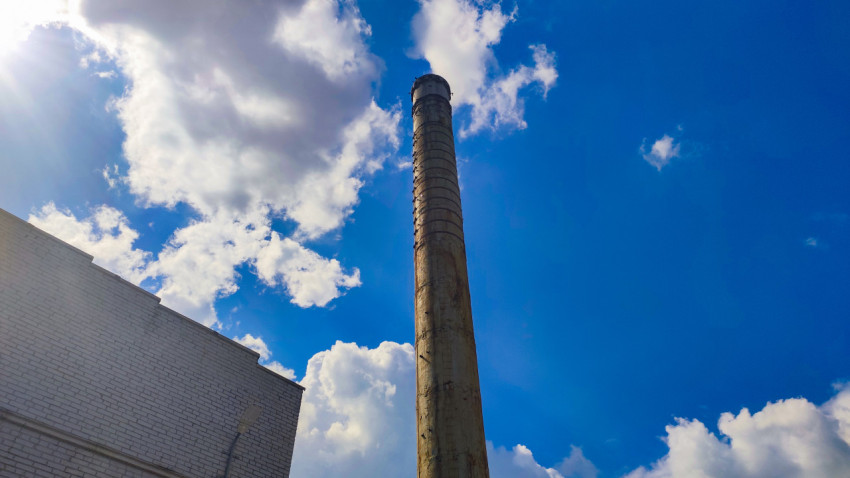 Высокая металлическая дымовая труба на фоне облачного неба