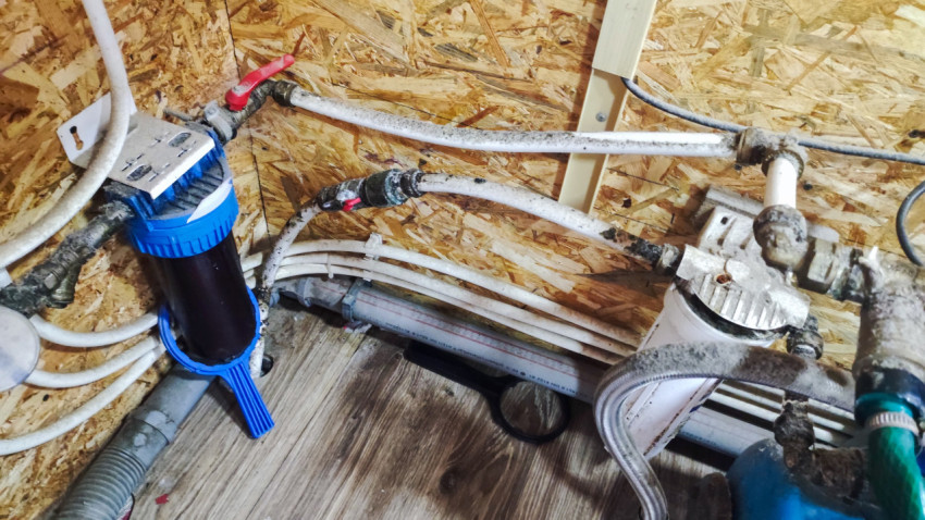 Узел водоснабжения с трубами и фильтрами в частном доме