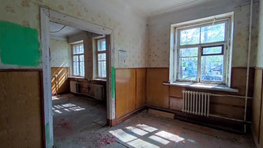 Освещённая комната с окнами и частично разобранной отделкой