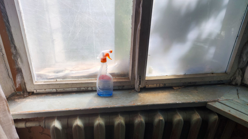 Подоконник с очистителем стекол и старой деревянной рамой