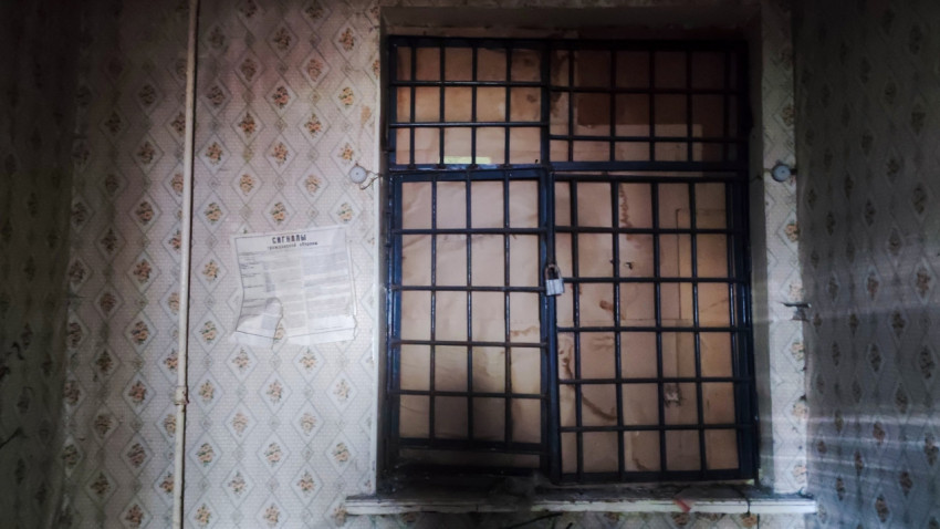 Окно с металлической решеткой и объявлением на стене