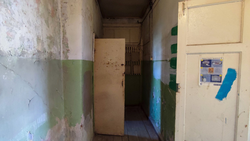 Коридор со старыми стенами и открытой дверью в помещении здания