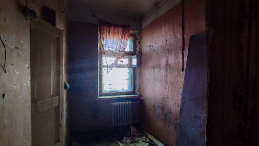 Комната с выбитыми стенами и окном с разрушенной шторой