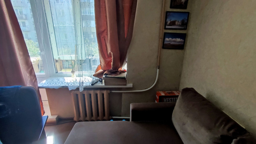 Угловая зона комнаты с окном, батареей и мебелью