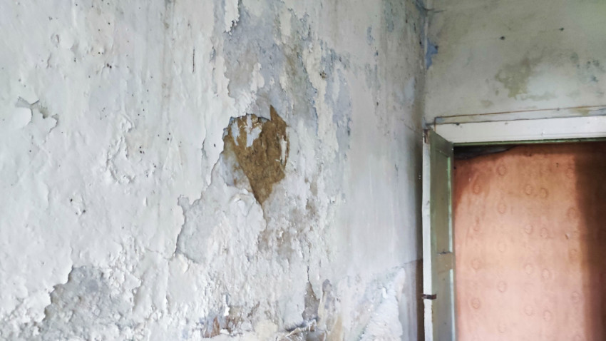 Поврежденная стена с облупившейся штукатуркой в старом помещении