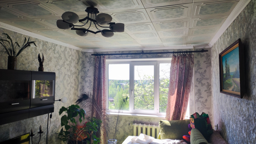 Гостиная с окном, портьерами и потолочными панелями