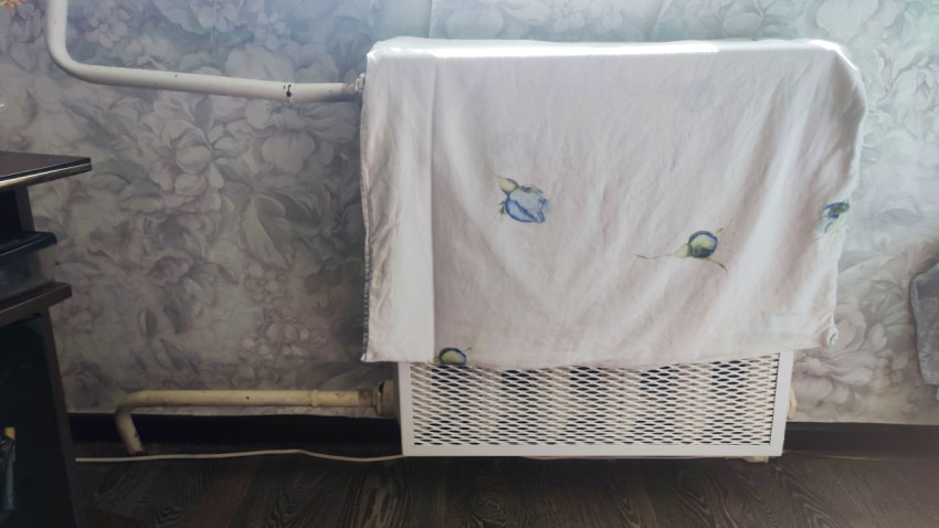 Радиатор отопления, закрытый тканью в жилой комнате