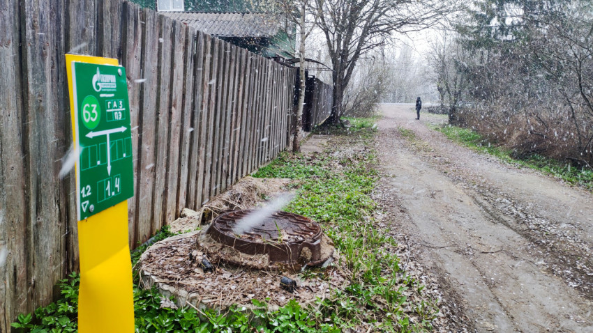 Газовый указатель и грунтовая дорога во время снегопада