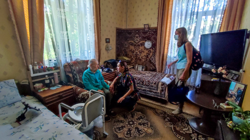 Комната с пожилым человеком, посетителями и настенным ковром