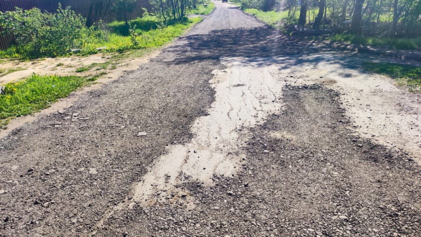Дорожный участок с размытым грунтовым покрытием и травяной обочиной