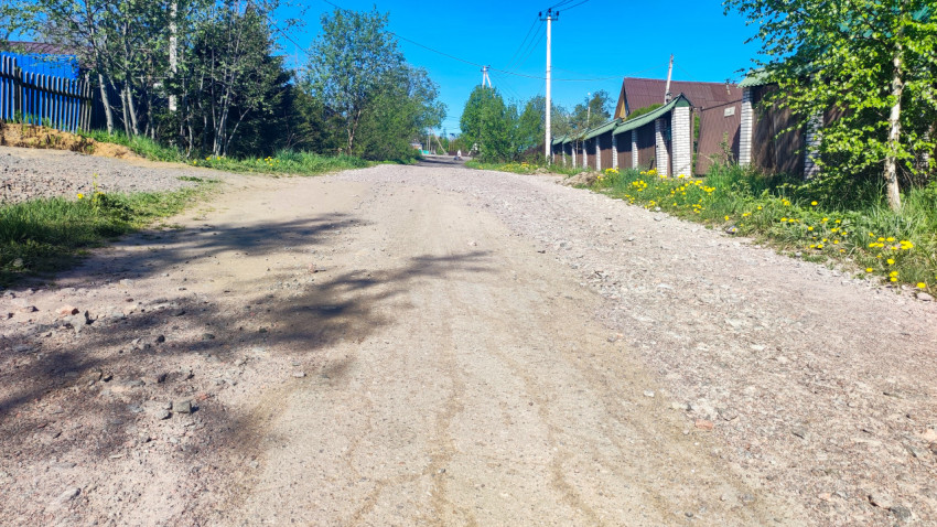Просёлочная дорога с неоднородным покрытием на окраине частного сектора