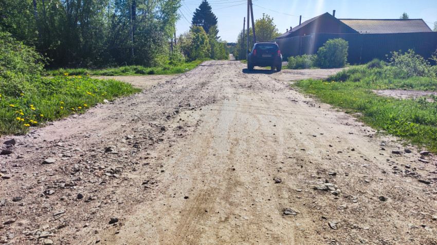 Просёлочная дорога с припаркованным автомобилем и зелёными обочинами