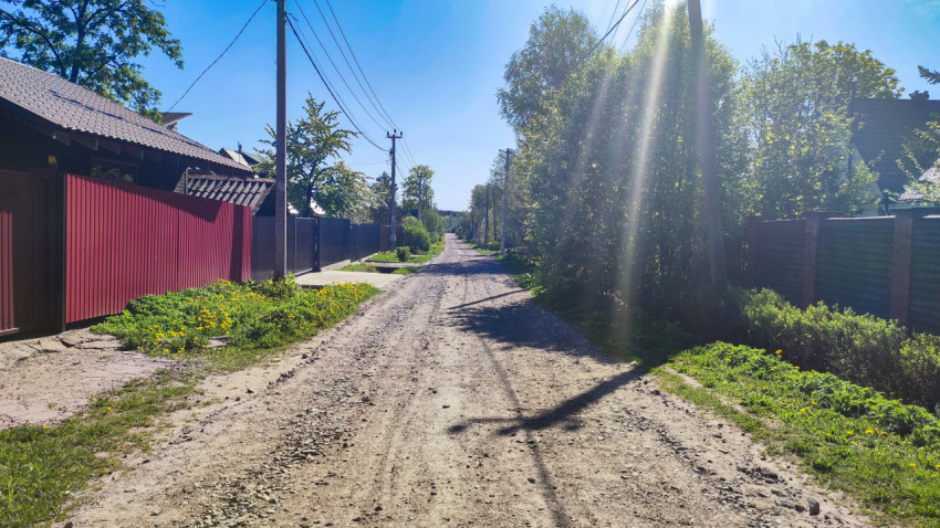 Загородная дорога с заборами частных участков и линиями электропередачи