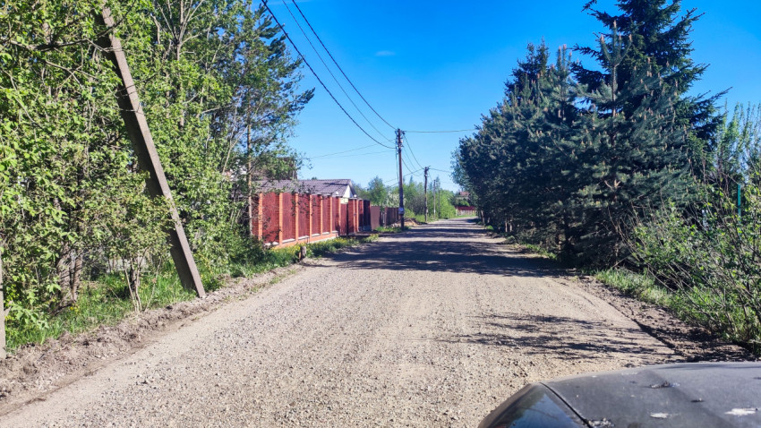 Грунтовая улица с частными домами и линиями электропередачи