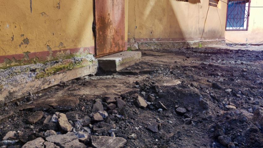 Участок стены здания и демонтированное дорожное покрытие во дворе