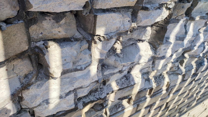 Фрагмент разрушенной кирпичной стены с осыпавшимися швами