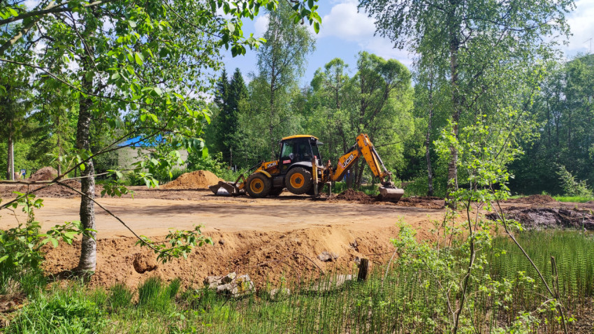 Экскаватор JCB на песчаной площадке у лесной опушки