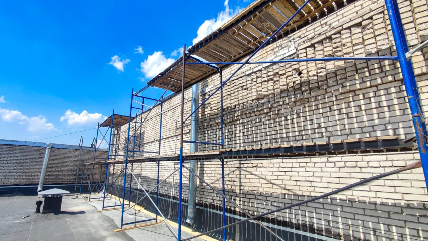 Строительные леса у фасада кирпичного здания на плоской крыше