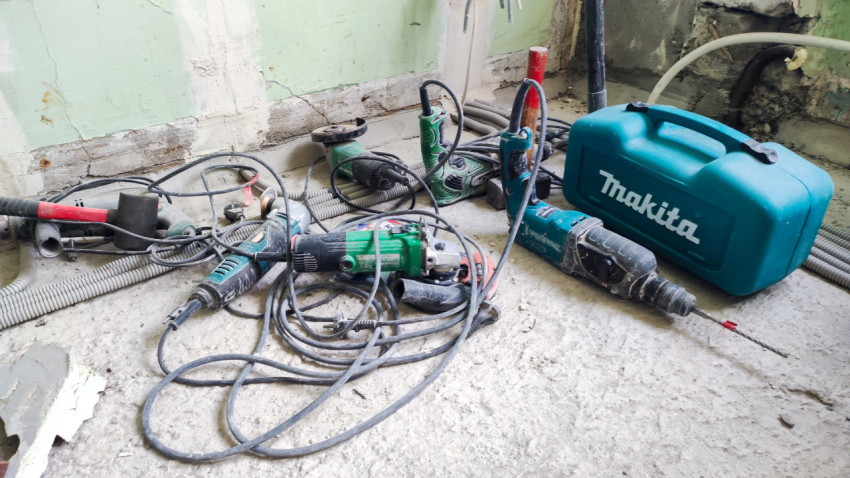 Электроинструменты и кабели на полу ремонтируемой комнаты
