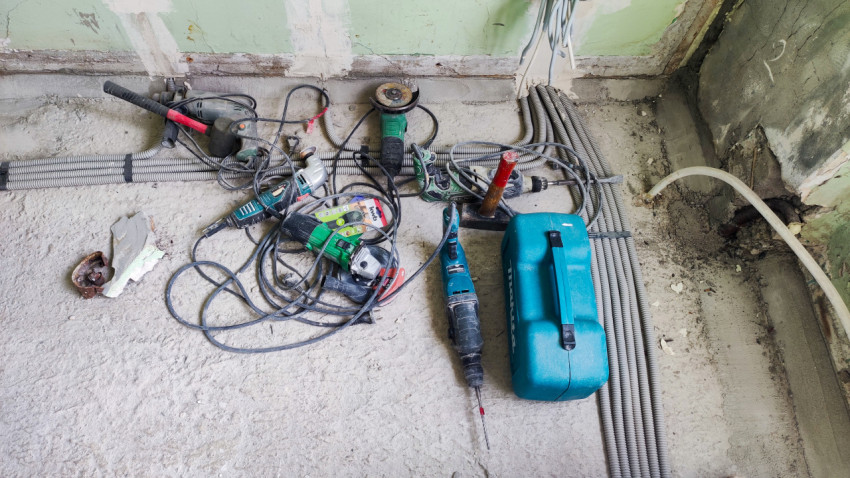Электроинструменты на полу рядом с гофротрубами в процессе ремонта
