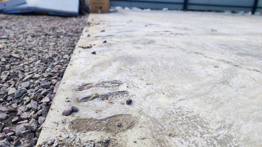 Следы на бетонной площадке и прилегающий участок гравия