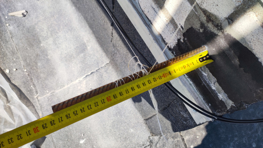 Замер элемента фасада с помощью рулетки на кровле здания