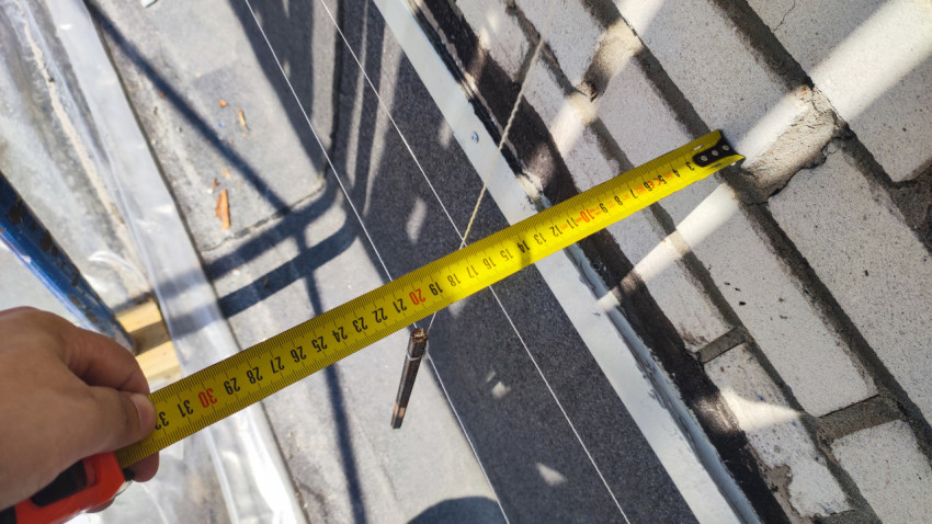 Замер расстояния на крыше возле кирпичной стены